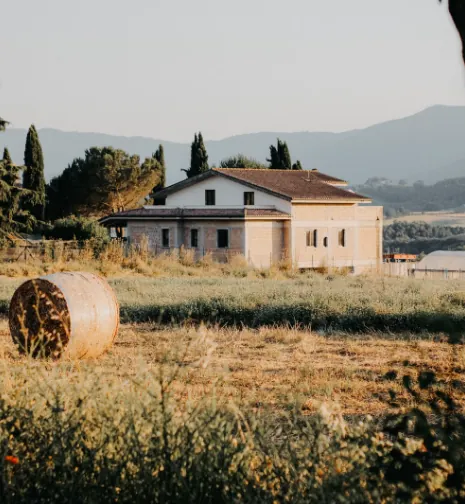 Casa di campagna tra cipressi e campi, con le colline sullo sfondo